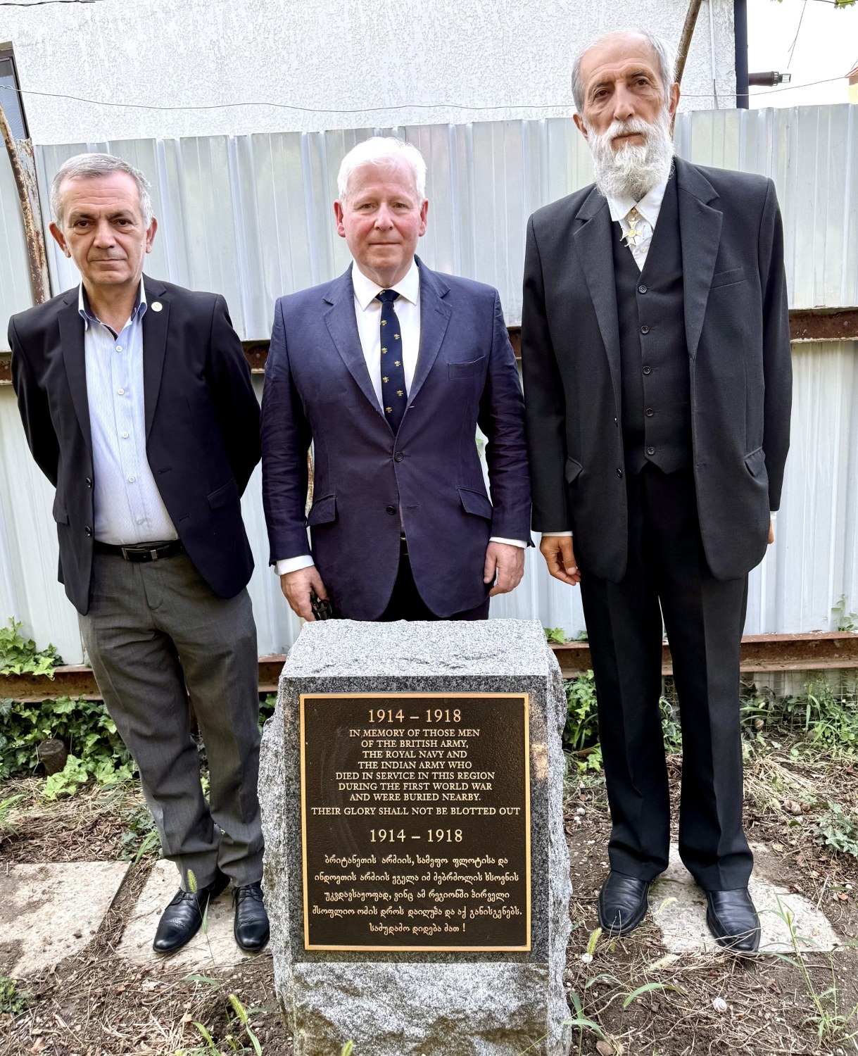 Three men standing by a war grave